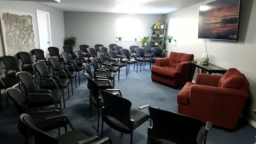 The Classroom Studio at CGW Studios, arranged with rows of padded ergonomic chairs facing a 72-inch flat screen and two red lounge chairs.